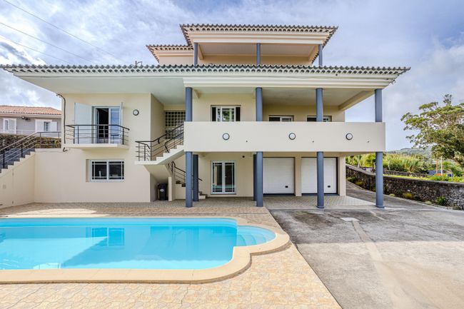 Fachada da moradia com piscina e garagem para dois carros